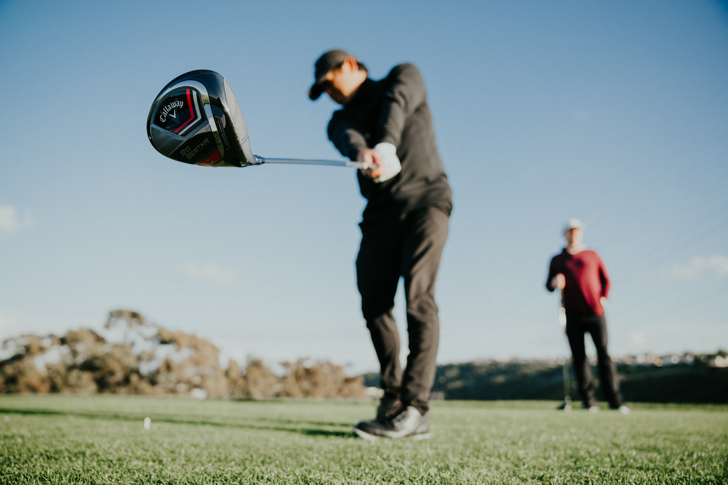 een golfer op een tee die de bal met zijn driver slaat