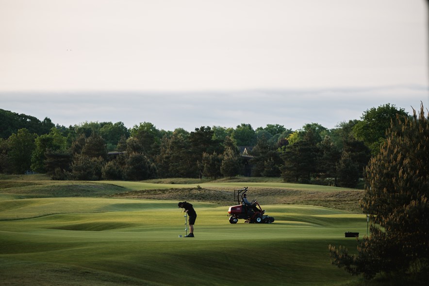 Greenkeeper steekt vlaggen uit in de green op Bernardus Golf