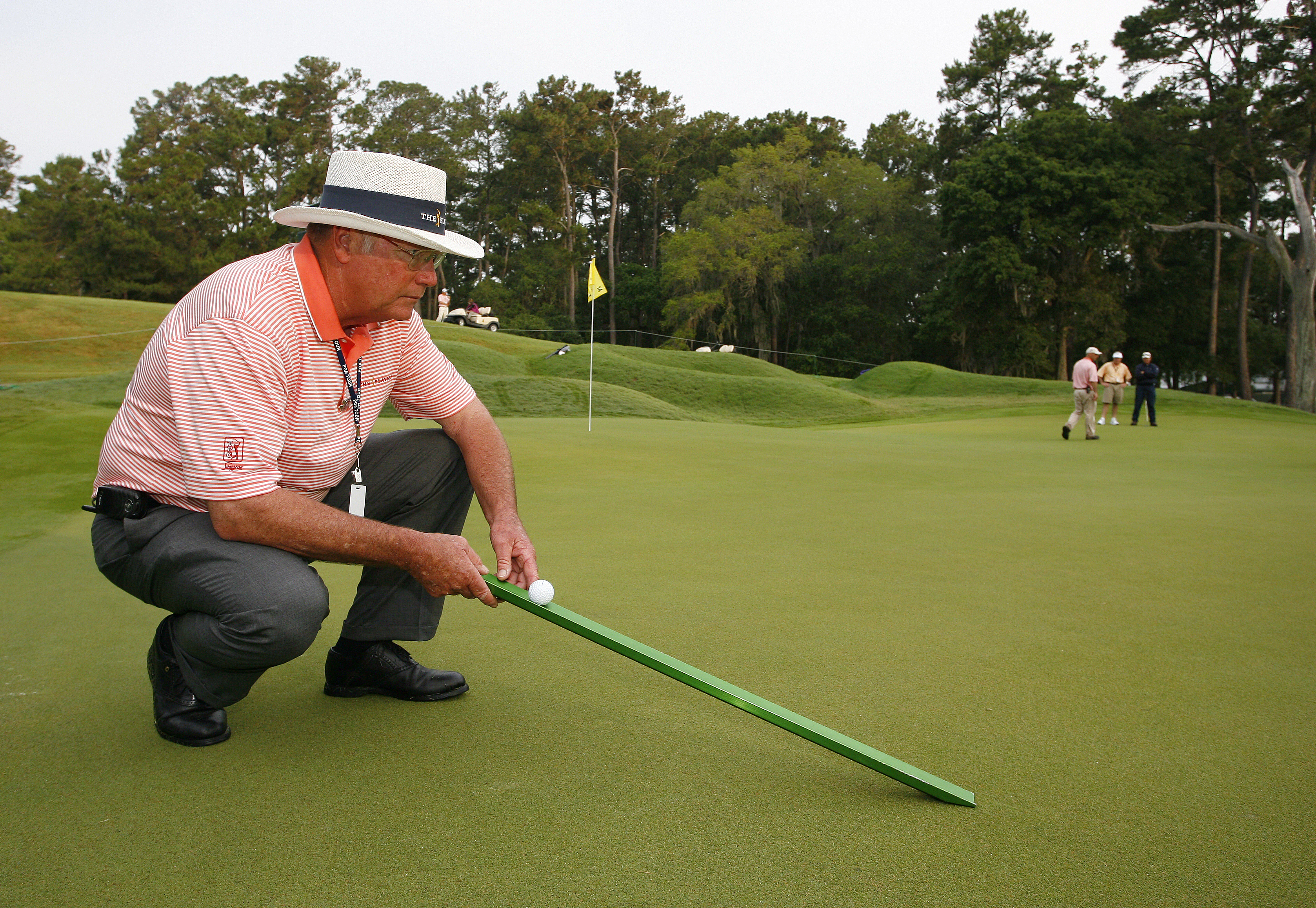 Een greenkeeper met een stimpmeter