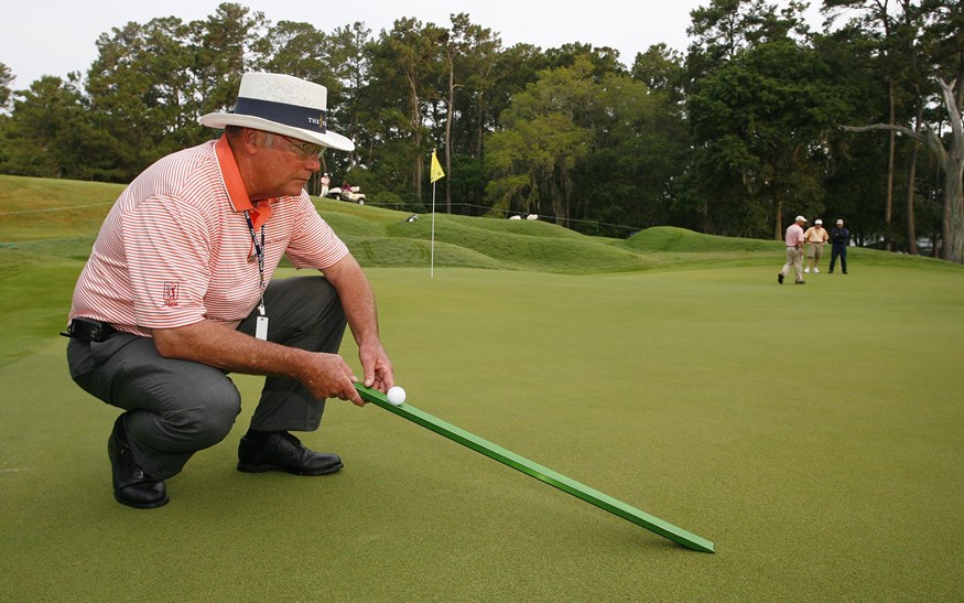 Een greenkeeper met een stimpmeter
